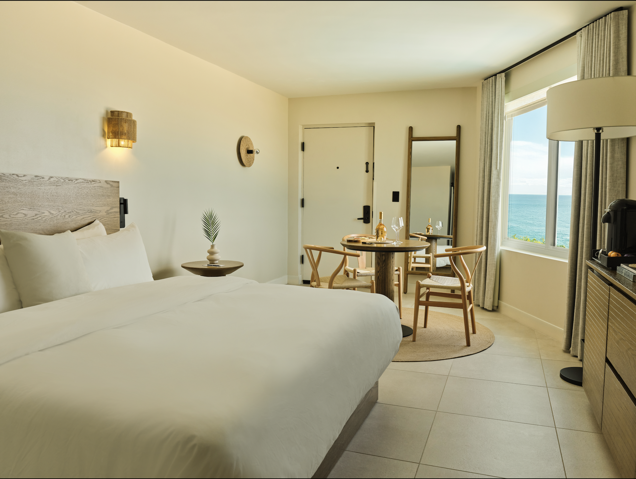 King Oceanfront Suite at Ambros Hotel with coastal views, king bed, sitting area, and natural light