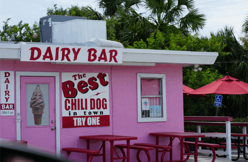 The Dairy Bar in Daytona Beach with pink exterior, red picnic tables, and a sign advertising chili dogs and ice cream