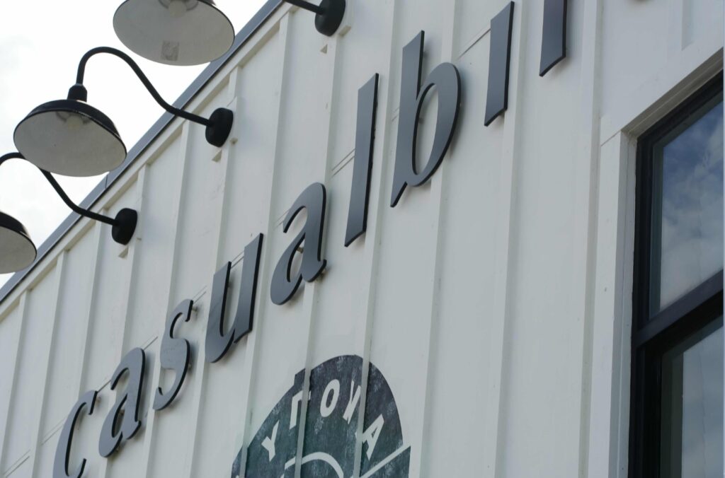Close-up of the Casual Bird Cafe sign on a white board-and-batten facade in Daytona Beach.