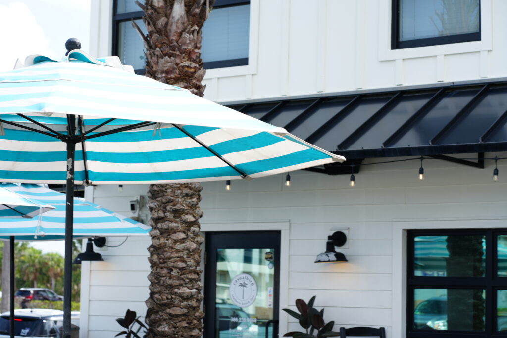Striped umbrellas and outdoor seating at Casual Bird Café in Daytona Beach Shores