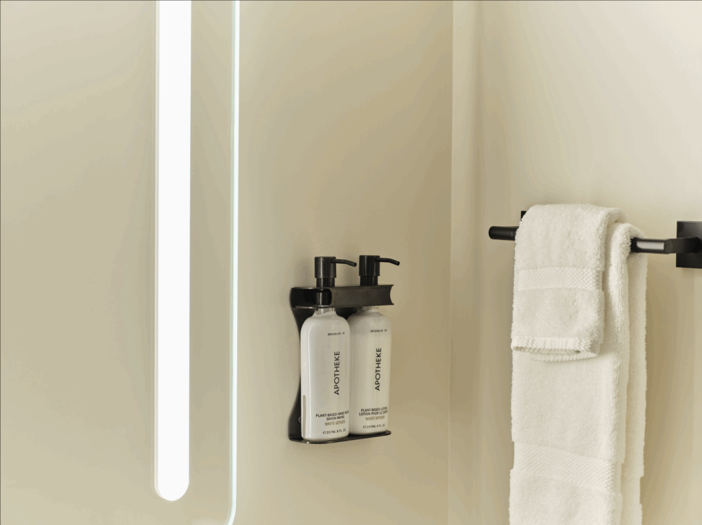 Apotheke plant-based lotion and folded white towels in a modern bathroom at Ambros Hotel