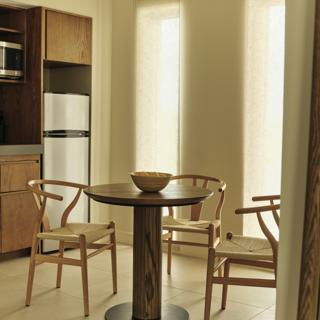 Kitchen and dining nook in the Corner King Suite at Ambros Hotel with wood cabinetry, microwave, mini-fridge, and modern seating