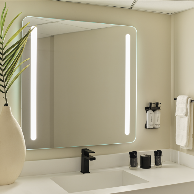 Accessible bathroom vanity in the ADA King Suite at Ambros Hotel with backlit mirror, towel bars, and modern decor