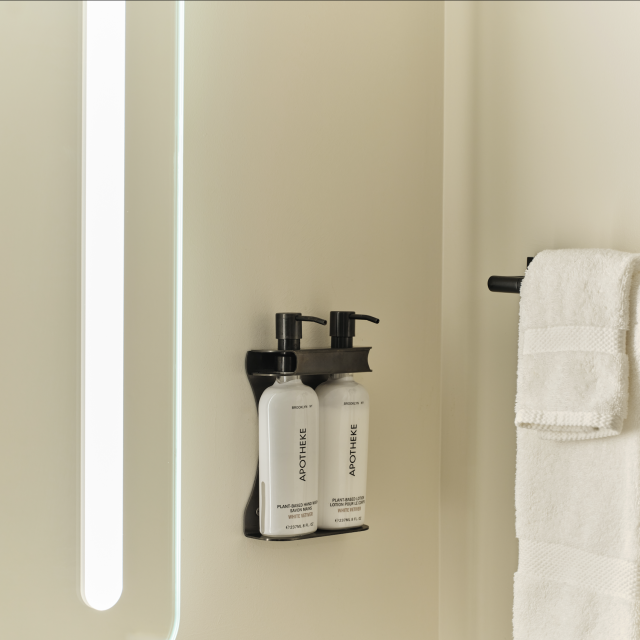 Apotheke plant-based lotion and folded white towels in a modern bathroom at Ambros Hotel